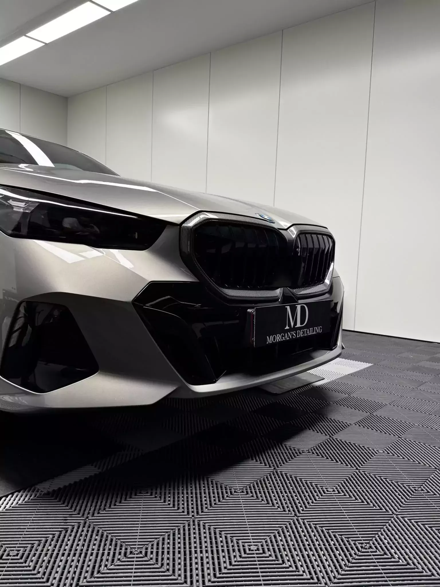 BMW i5 grise protégée par un film PPF, face avant dans l’atelier