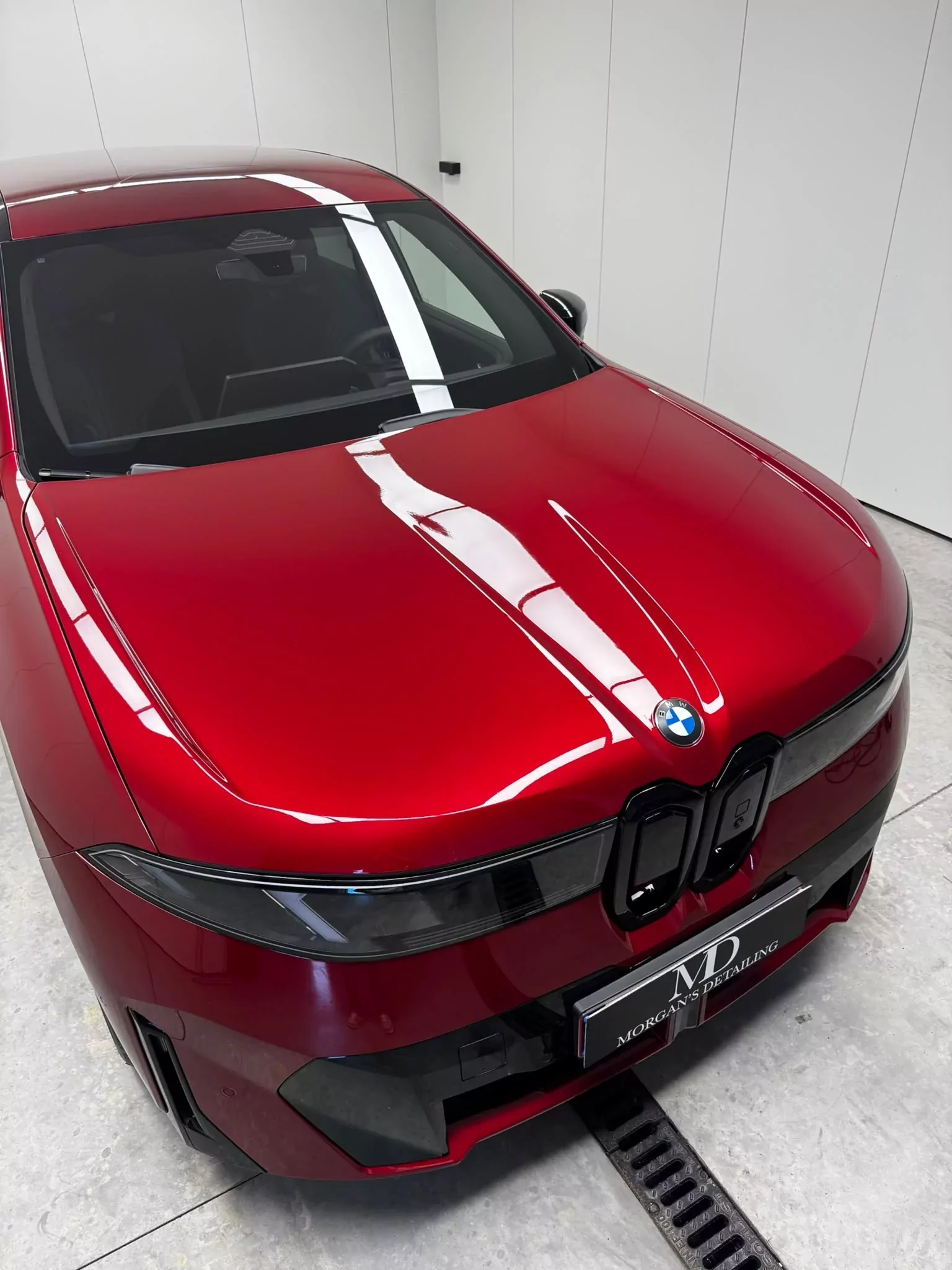 Capot de la BMW iX rouge après pose de PPF, reflets des néons
