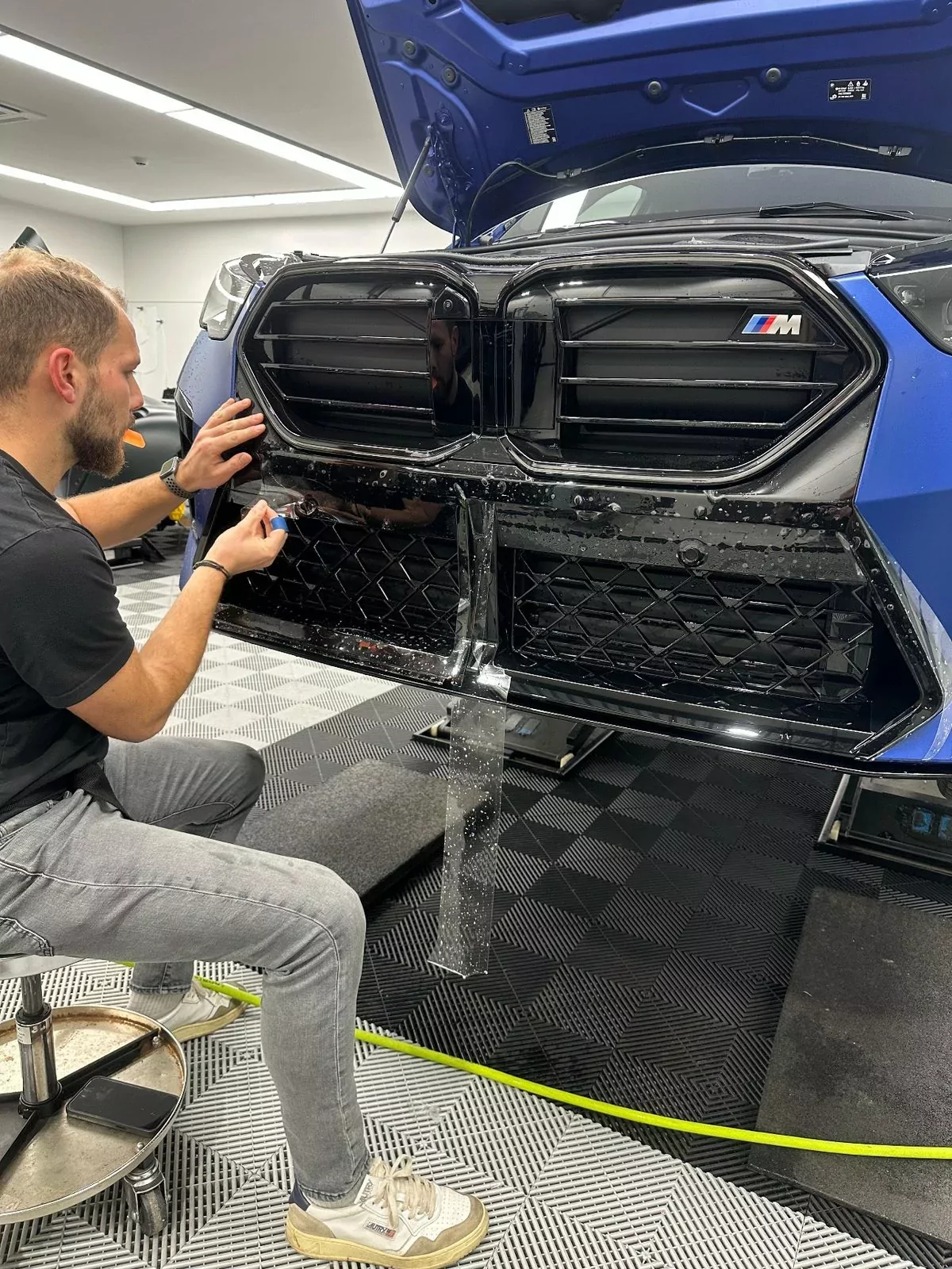 Pose d’un film PPF sur la calandre d’un SUV, à l’atelier de Fernelmont