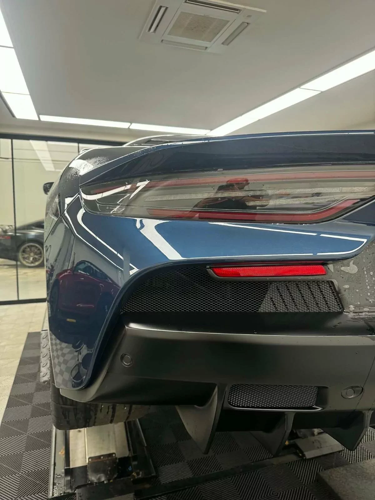 Namur : arrière d’une carrosserie bleue après pose du film PPF, sous les lumières de l’atelier